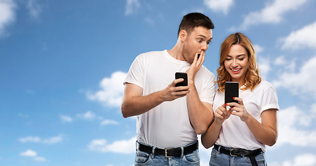 Image showing happy couple in white t-shirts with smartphones