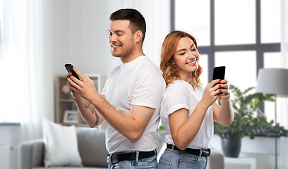 Image showing happy couple in white t-shirts with smartphones