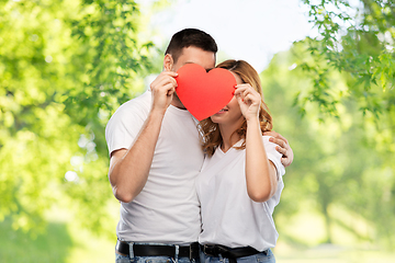 Image showing smiling couple hiding behind big red heart