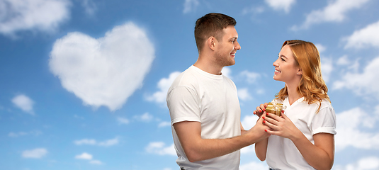 Image showing happy couple in white t-shirts with gift