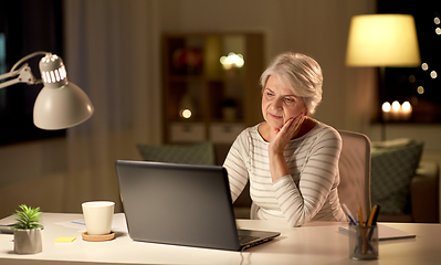 Image showing senior woman with laptop at home in evening