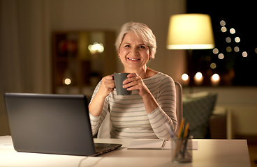 Image showing senior woman with laptop drinking coffee at home