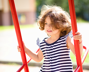 Image showing Young happy girl is swinging in playground