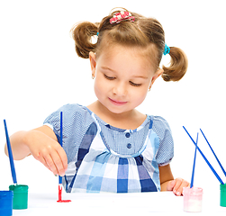 Image showing Little girl is painting with gouache