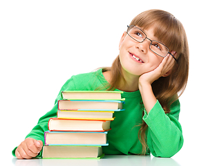 Image showing Young girl is daydreaming while reading book