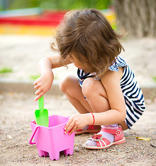 Image showing Little girl is playing with sand in playground