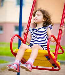 Image showing Young girl is swinging in playground