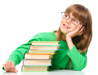 Image showing Young girl is daydreaming while reading book