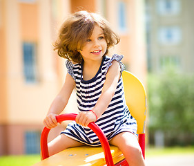 Image showing Young happy girl is swinging in playground