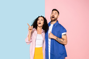 Image showing Young emotional man and woman on pink and blue background