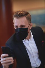 Image showing business man using smart phone at luxury office wearing face mask