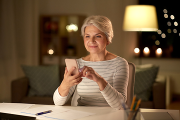 Image showing senior woman with smartphone at home at night