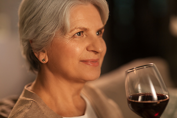 Image showing senior woman drinking red wine at home in evening