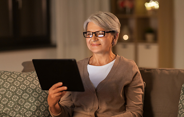 Image showing happy senior woman with tablet pc at home at night