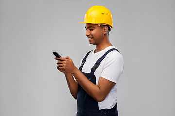 Image showing happy indian or builder in helmet using smartphone