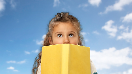 Image showing little girl hiding behind yellow book