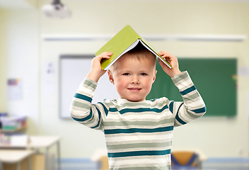 Image showing smiling boy with book on head at school