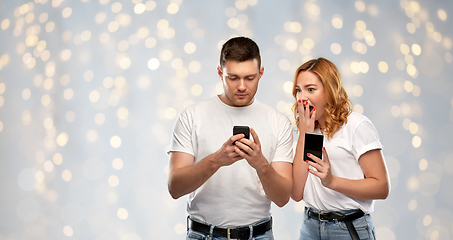 Image showing happy couple in white t-shirts with smartphones