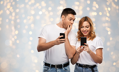 Image showing happy couple in white t-shirts with smartphones