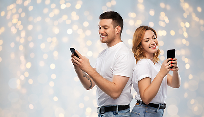 Image showing happy couple in white t-shirts with smartphones