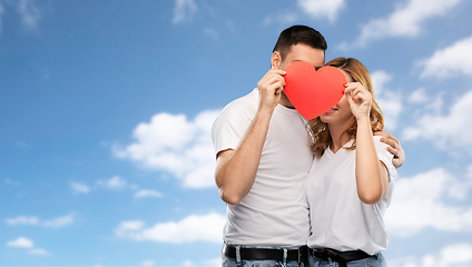 Image showing smiling couple hiding behind big red heart