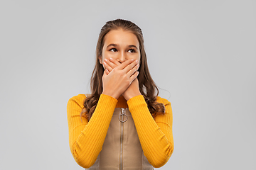 Image showing scared teenage girl closing her mouth by hands