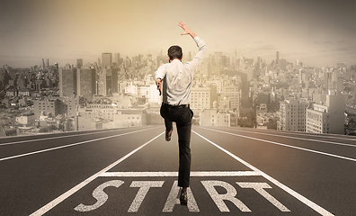 Image showing Businessman jumping on a starting grid with cityscape on the background