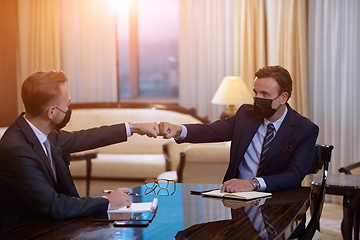 Image showing business people wearing face mask on meeting and handshake