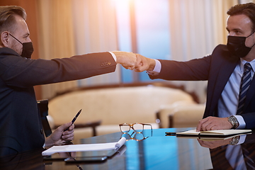 Image showing business people wearing face mask on meeting and handshake