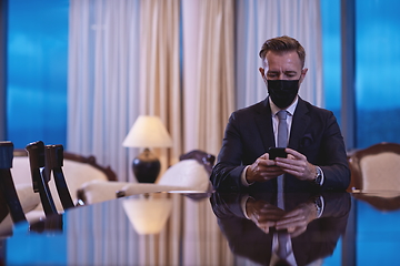 Image showing business man using smart phone at luxury office wearing face mask