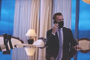 Image showing business man using smart phone at luxury office wearing face mask