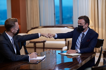 Image showing business people wearing face mask on meeting and handshake