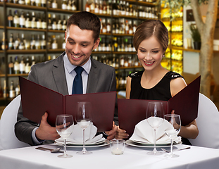 Image showing smiling couple with menus at restaurant