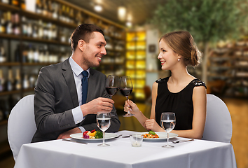 Image showing smiling couple clinking wine glasses at restaurant