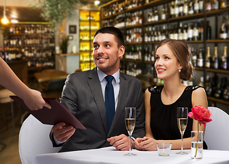 Image showing waiter giving menu to happy couple at restaurant