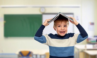 Image showing little boy with book on top of his head at school