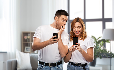 Image showing happy couple in white t-shirts with smartphones