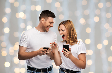 Image showing happy couple in white t-shirts with smartphones