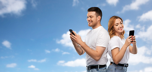 Image showing happy couple in white t-shirts with smartphones