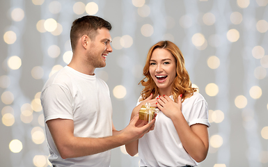 Image showing happy couple in white t-shirts with christmas gift