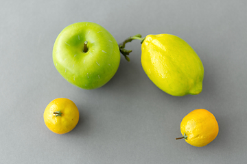 Image showing close up of green apple and lemons on grey