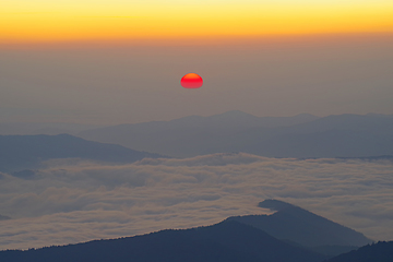 Image showing Sunrise scene with red sun over the mountains