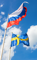 Image showing Russian and Sweden flags waving against the blue sky