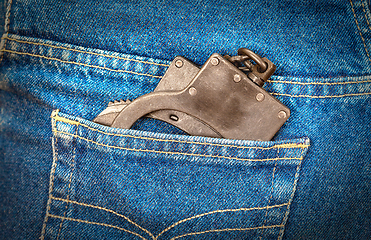 Image showing Black metal handcuffs in back jeans pocket