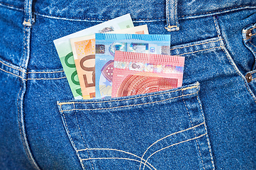 Image showing Euro banknotes sticking out of the blue jeans pocket. Money for 