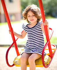 Image showing Young happy girl is swinging in playground