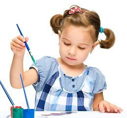 Image showing Little girl is painting with gouache