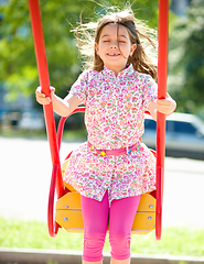 Image showing Young happy girl is swinging in playground