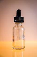 Image showing Glass dropper bottle on orange background