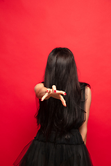 Image showing Young woman in hat and dress as a witch on red background